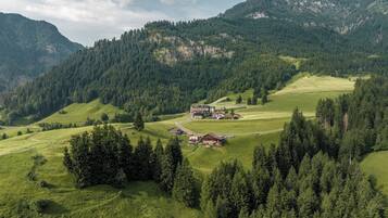 Paisaje rural con un grupo de edificios rodeados de bosques densos y colinas ondulantes.