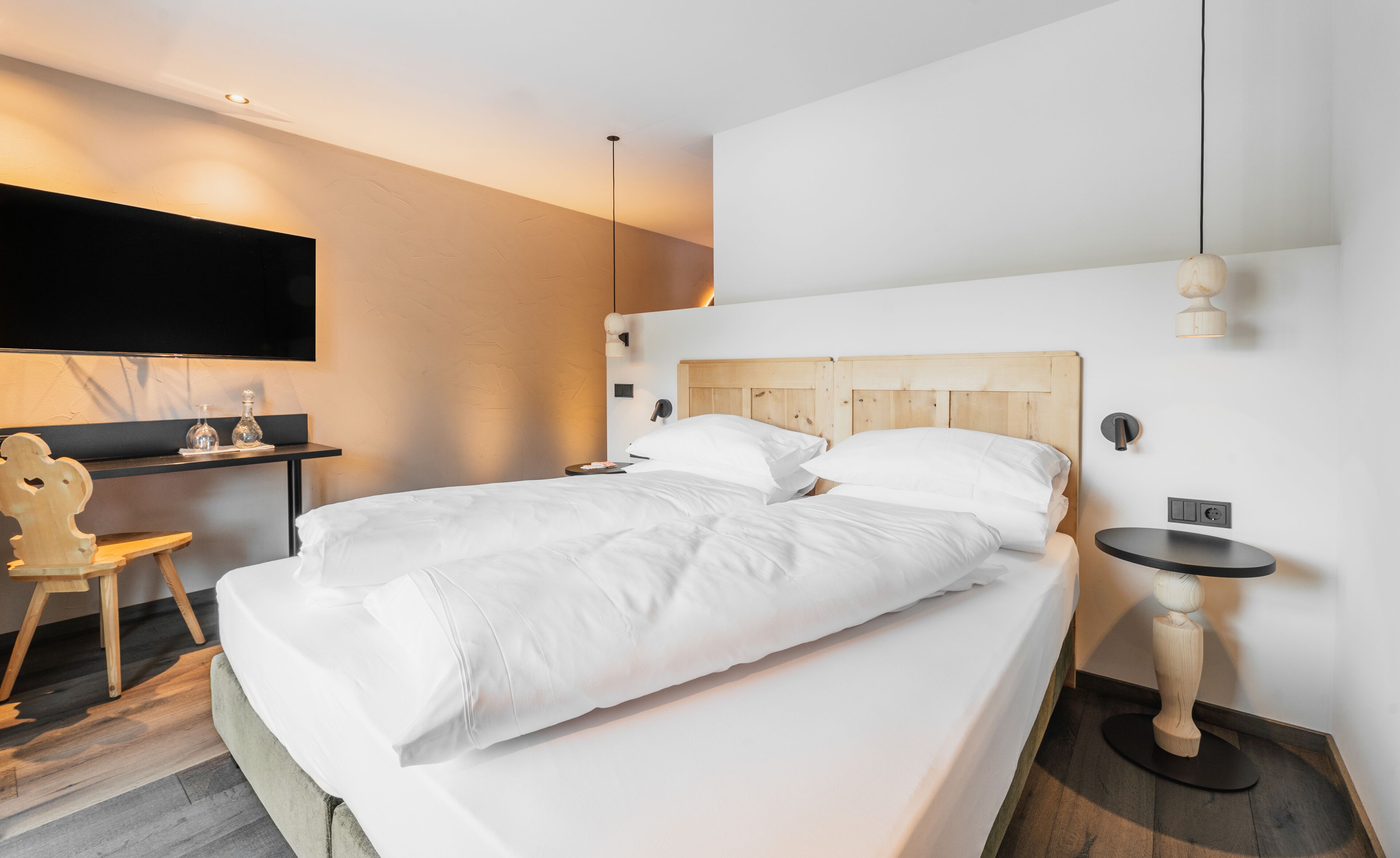 Une chambre d’hôtel moderne, dotée d’un grand lit, d’un bureau, d’une chaise et d’un téléviseur fixé au mur.