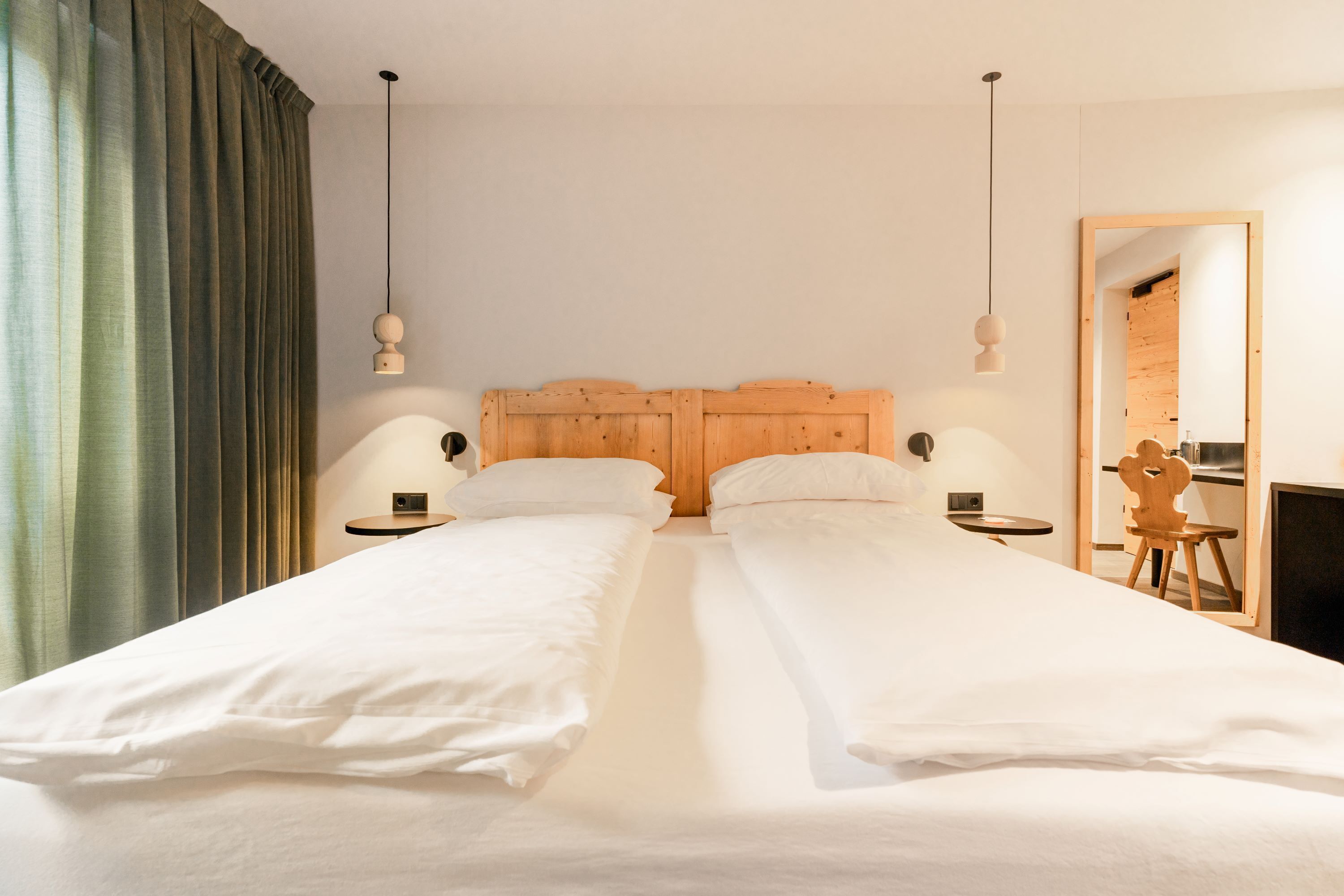 A double bed with wooden headboard, two bedside tables, and a mirror on the wall.
