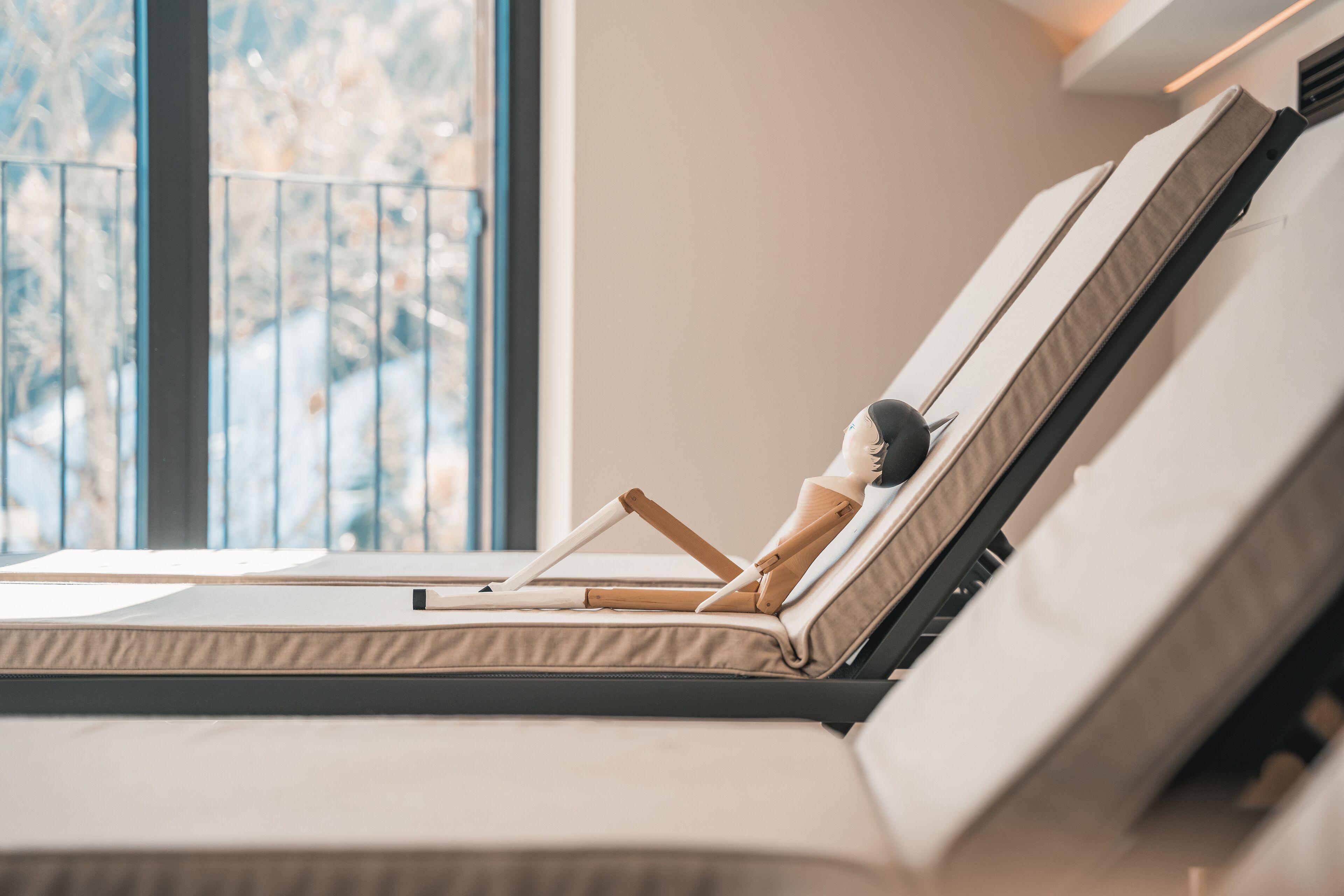 Una habitación moderna con un ventanal grande, una cama con cabecera de madera y una pequeña mesa con un libro.