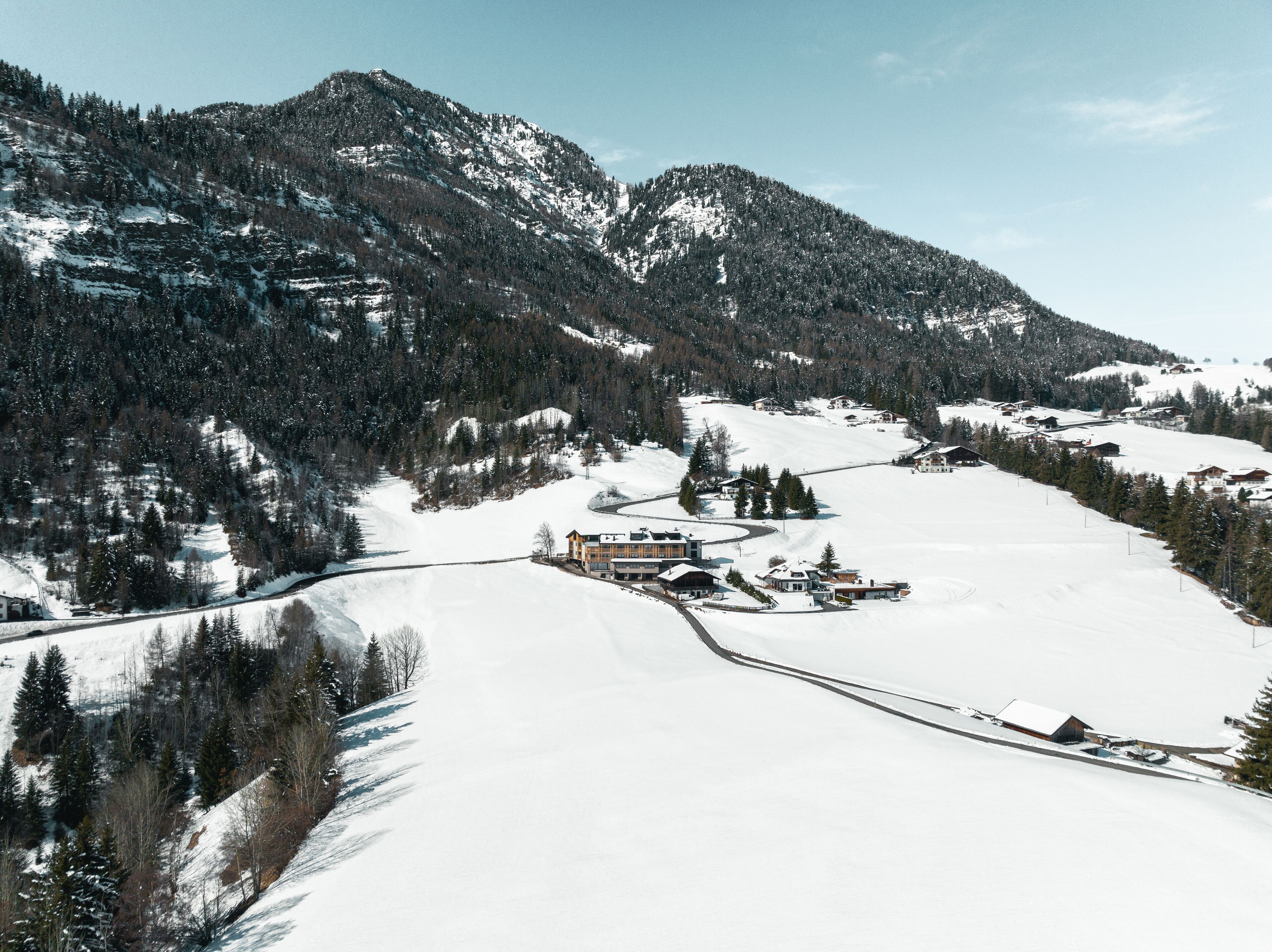 Paisaje montañoso cubierto de nieve con una estación de esquí, que incluye edificios y pistas de esquí.