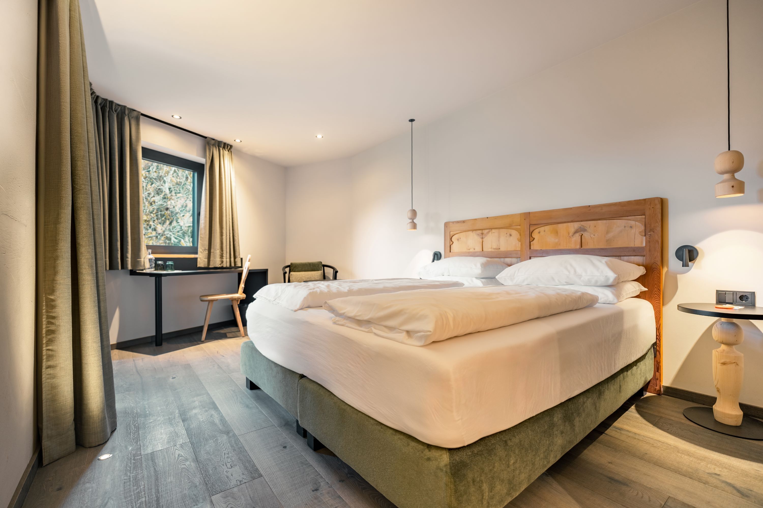 Une chambre moderne avec un grand lit, un bureau et une fenêtre avec des rideaux.