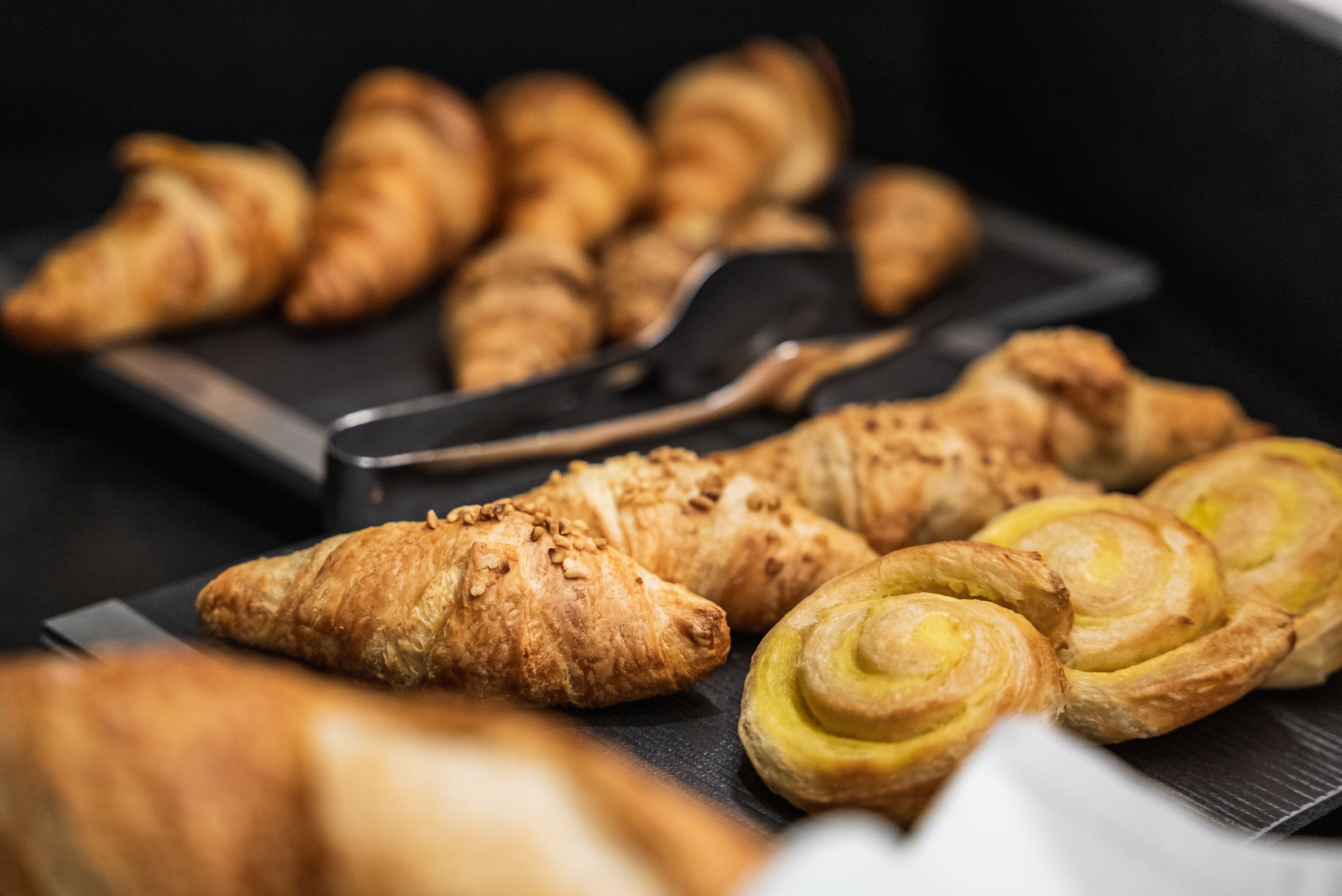 Une variété de viennoiseries présentées sur un plateau, notamment des croissants et des chaussons.