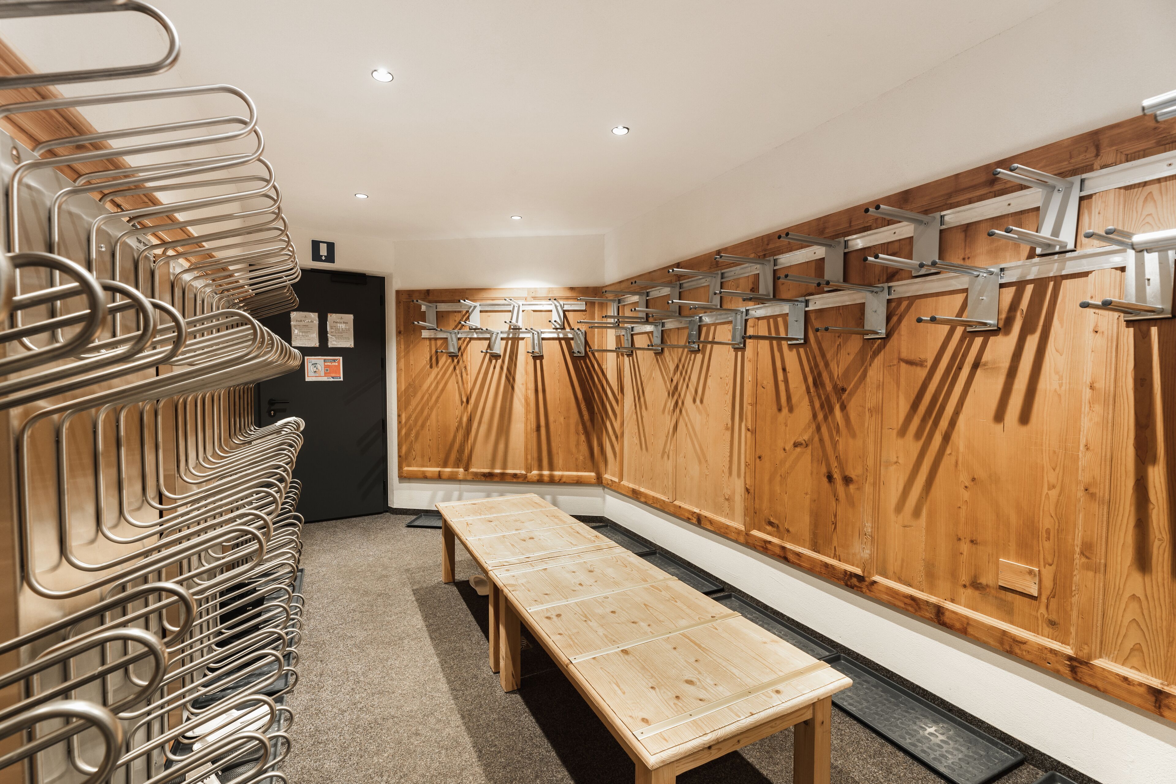 Un baño moderno con toalleros metálicos, bancos de madera y una pared de madera.