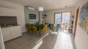 A modern kitchen with white cabinets and a dining area with yellow chairs.