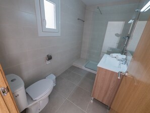 A bathroom with a toilet, a glass shower enclosure, and a sink with a mirror. - Peater Plaza - Two Bedroom Apartment, Sleeps 5 (Roses)