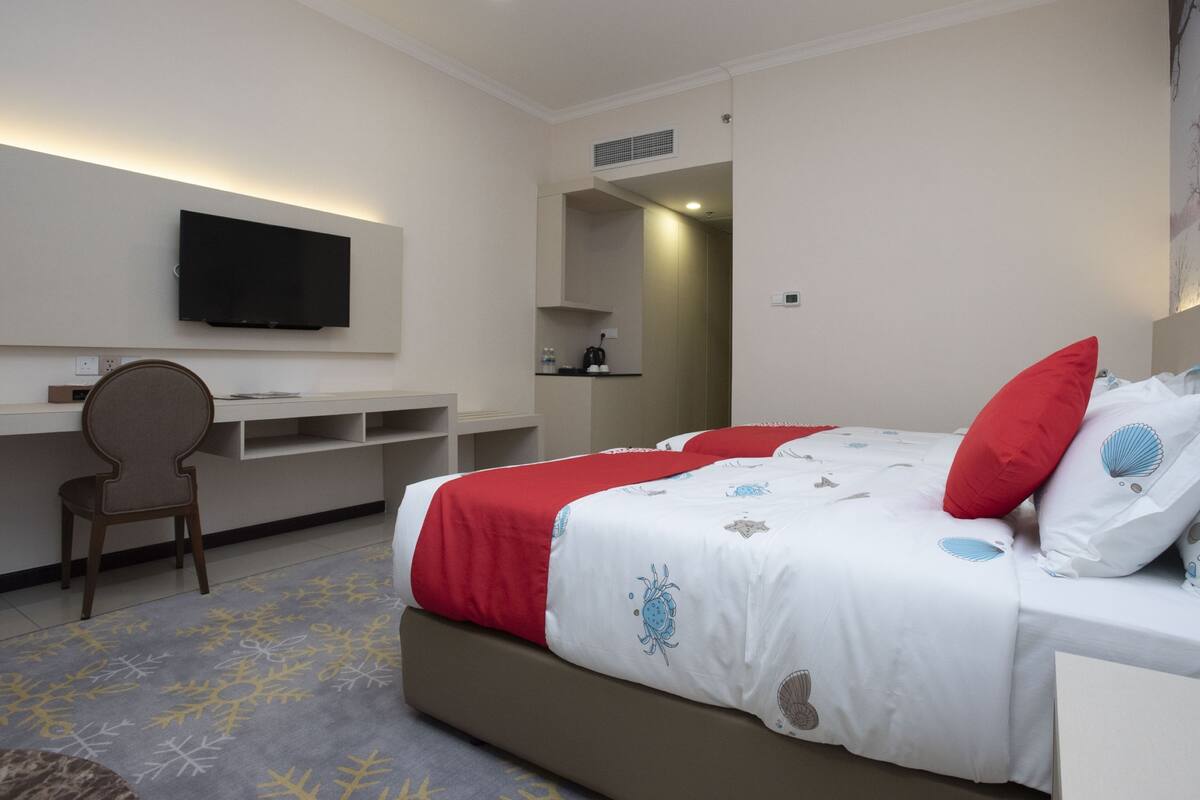 A hotel room with a bed, a desk, and a TV.