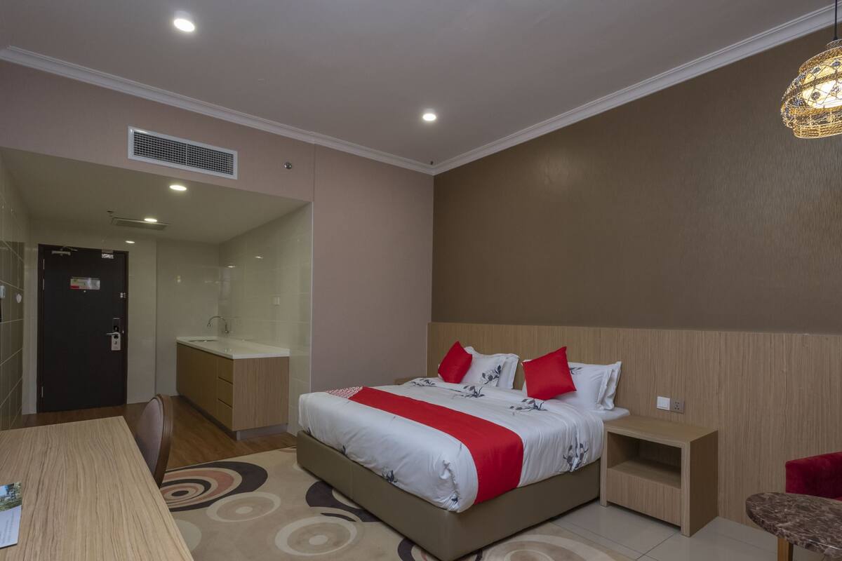 A modern hotel room with a large bed, bedside tables, a desk, and a shower area.