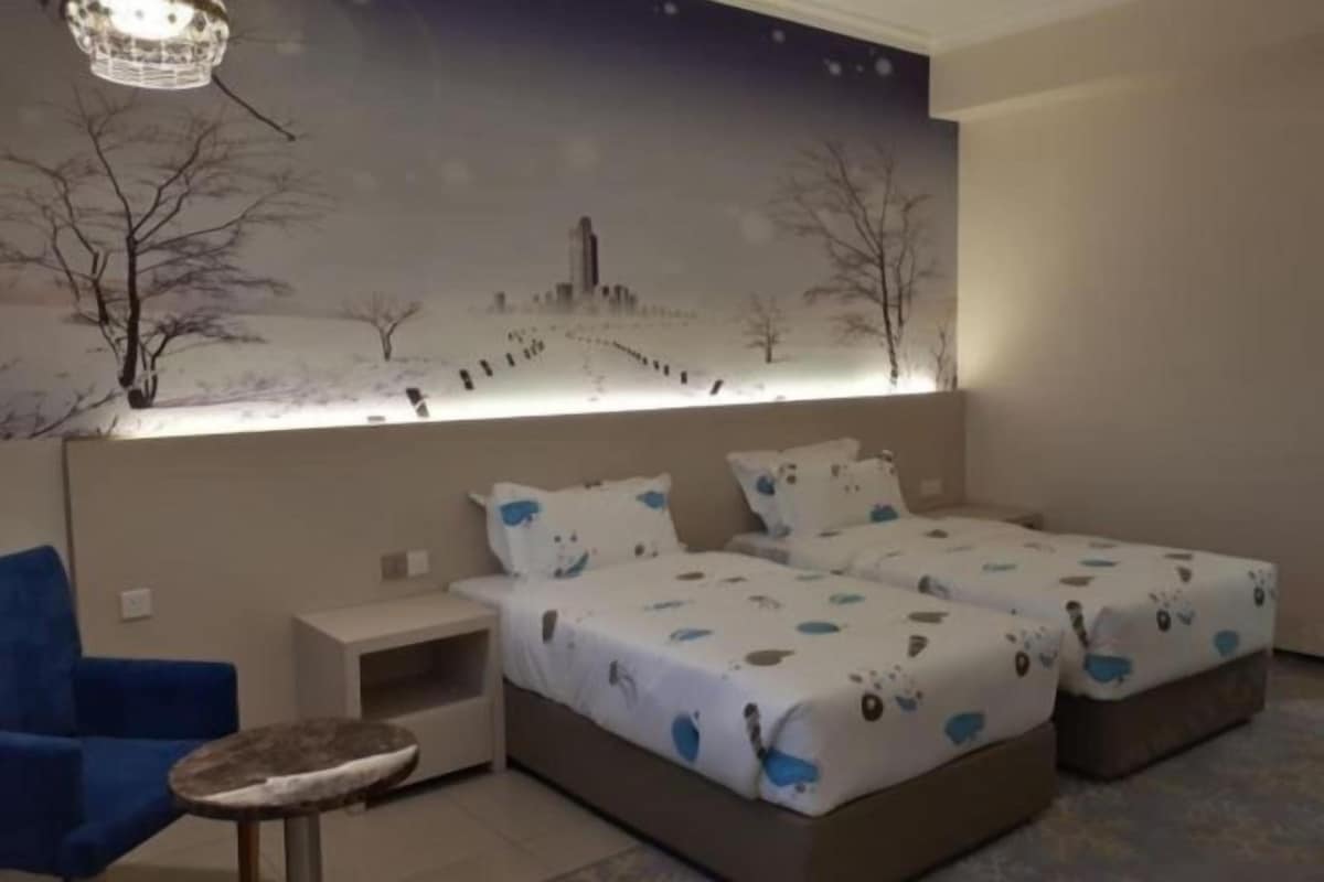 Ein Schlafzimmer mit zwei Betten, einem Nachttisch, einem Stuhl und einem Wandregal.