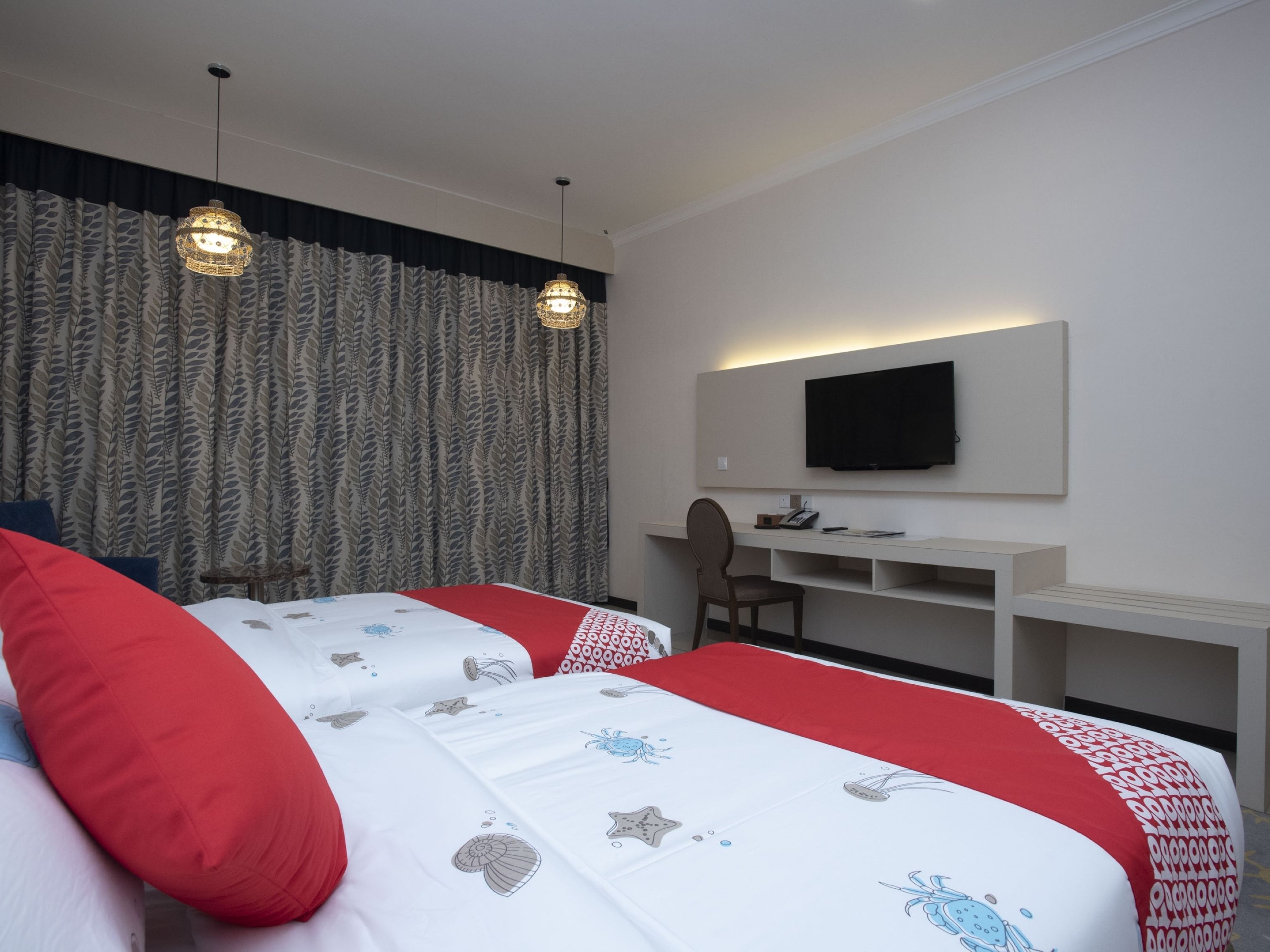 A hotel room with a bed, a desk, and a television.