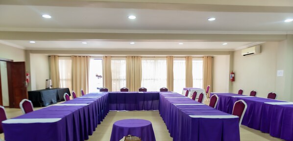 A conference room with long tables covered in purple tablecloths, arranged in a U-shape. - Nomad's Court Lodge (Lusaka)