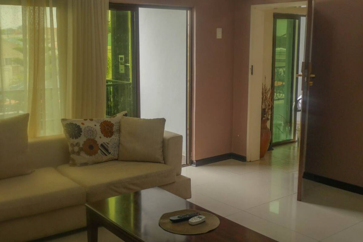A living room with a sofa, a coffee table, and a sliding glass door leading to a balcony.