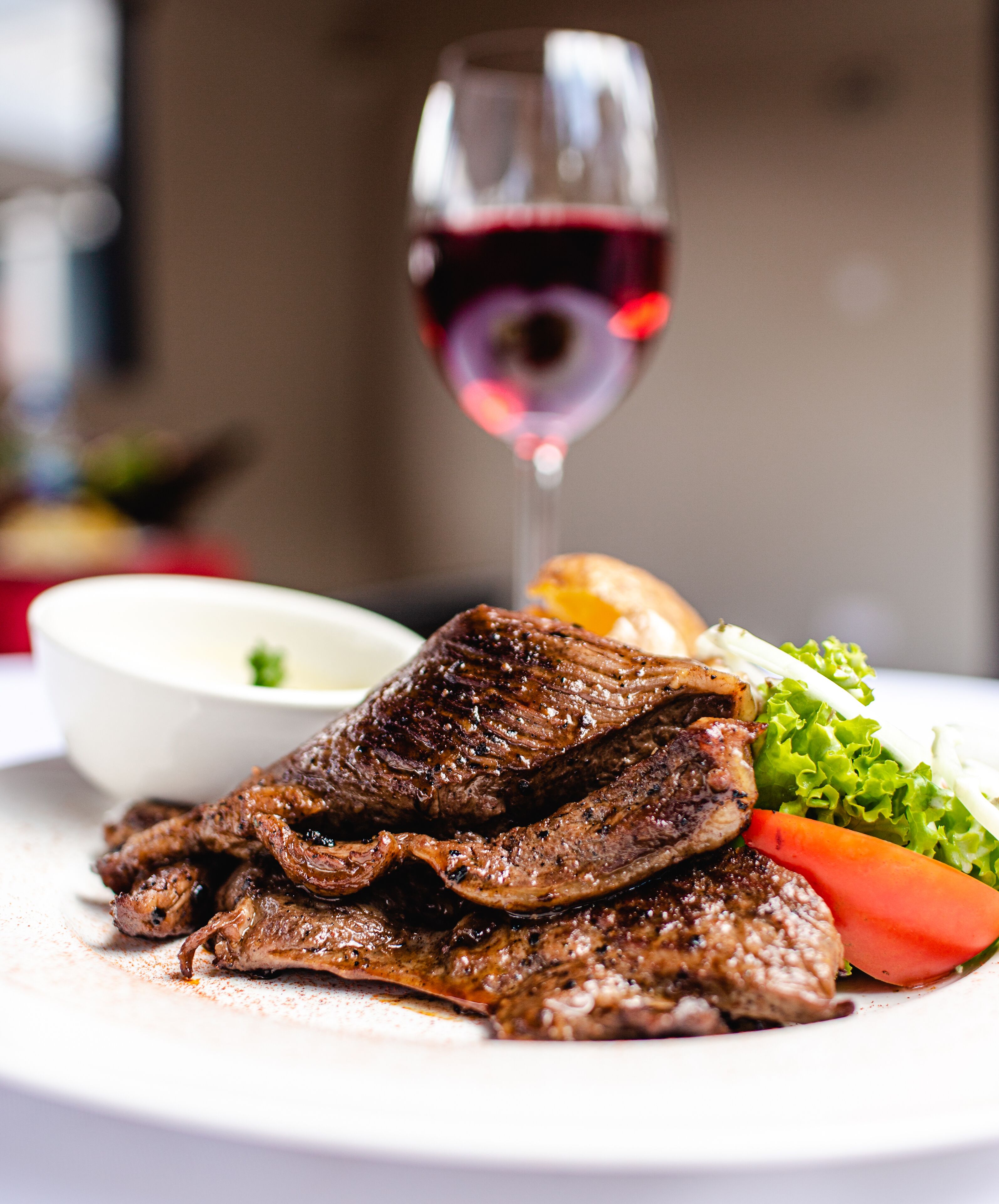 A plate of grilled meat with vegetables and a glass of red wine.