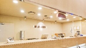 A reception area with a counter, a bench, and a ceiling with recessed lighting. - Maebashi Hotel (Maebashi)
