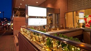 An indoor restaurant with brick walls, a glass railing, and a Christmas decoration. - Maebashi Hotel (Maebashi)
