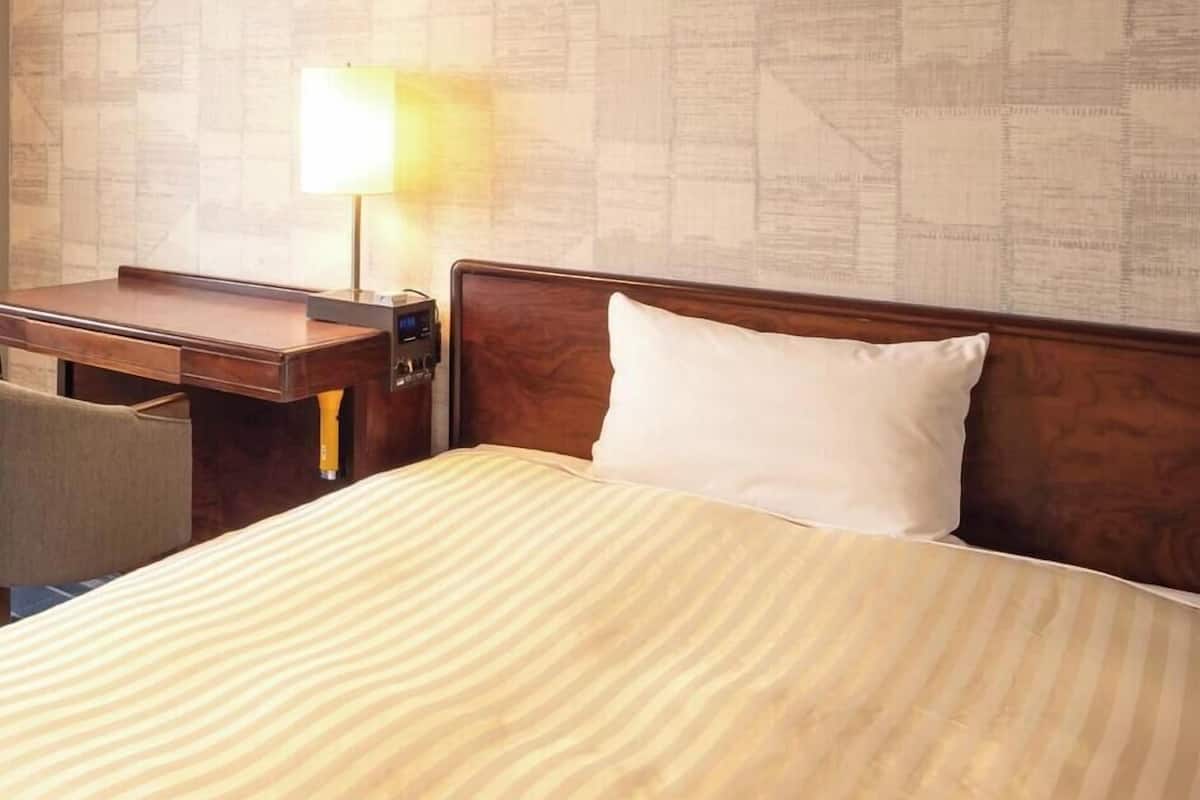 A hotel room with a bed, a desk, and a chair.