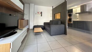 A modern living room with a flat-screen TV, grey sofa, and a wooden coffee table. - Drugstore B A - Two Bedroom Apartment, Sleeps 6 (Roses)
