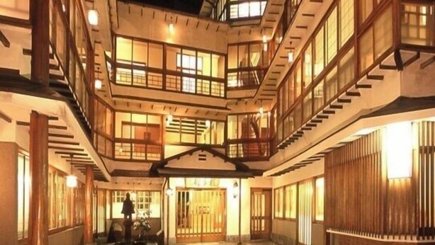 Ein mehrgeschossiges Gebäude mit Innenhof, Holzgeländern und einer Treppe.