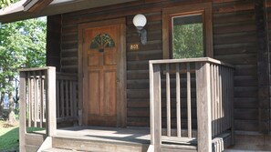 A wooden cabin with a large front door, a small porch with railings, and a number '801' above the door.