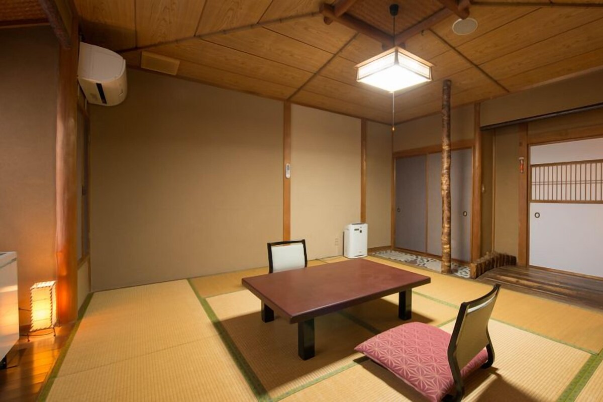 A traditional Japanese room with tatami flooring, a low table, and a chair.