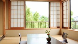 Une pièce avec un sol recouvert de tatamis, une petite table, une chaise et un luminaire suspendu.