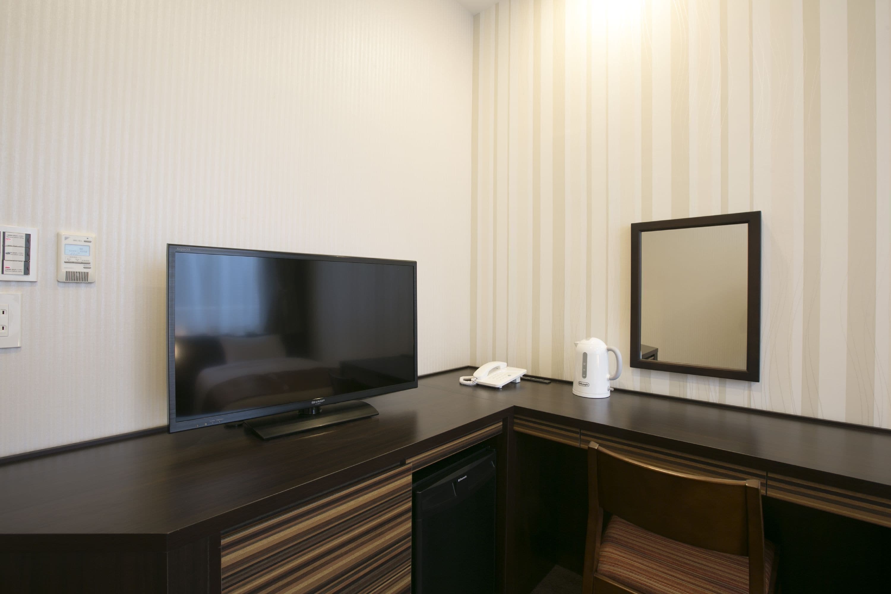 Habitació d'hotel amb televisió de pantalla plana, telèfon, cafetera i mirall a la paret.