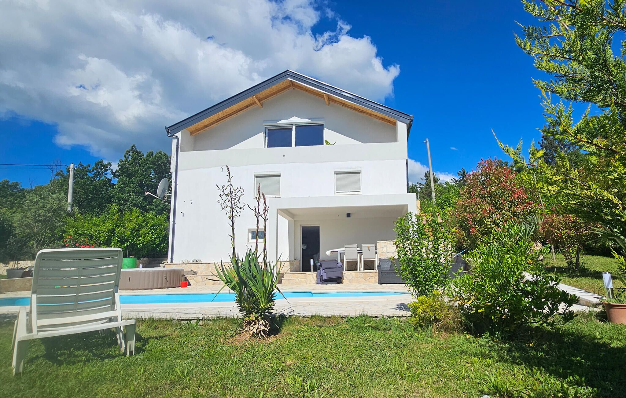 A two-story house with a balcony, a swimming pool, and a garden.