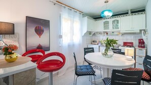 Een moderne keuken met witte kasten, een ronde eettafel en rode stoelen.