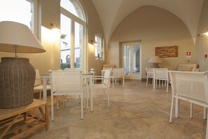 A spacious room with white furniture, large windows, and a tiled floor. - I Pretti Resort (Favignana)