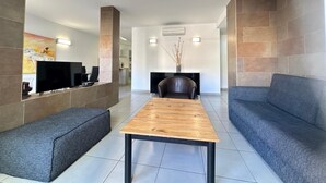A modern living room with a flat-screen TV, a wooden coffee table, grey sofas, and a fireplace.