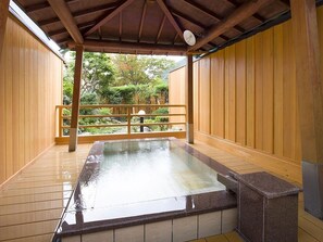 A hot spring bath area with wooden walls and a tiled floor. - Kirakuya Inn (Koriyama)