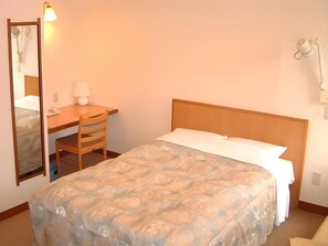 A hotel room with a bed, a desk, a chair, a mirror, and a lamp. - Kirakuya Inn (Koriyama)