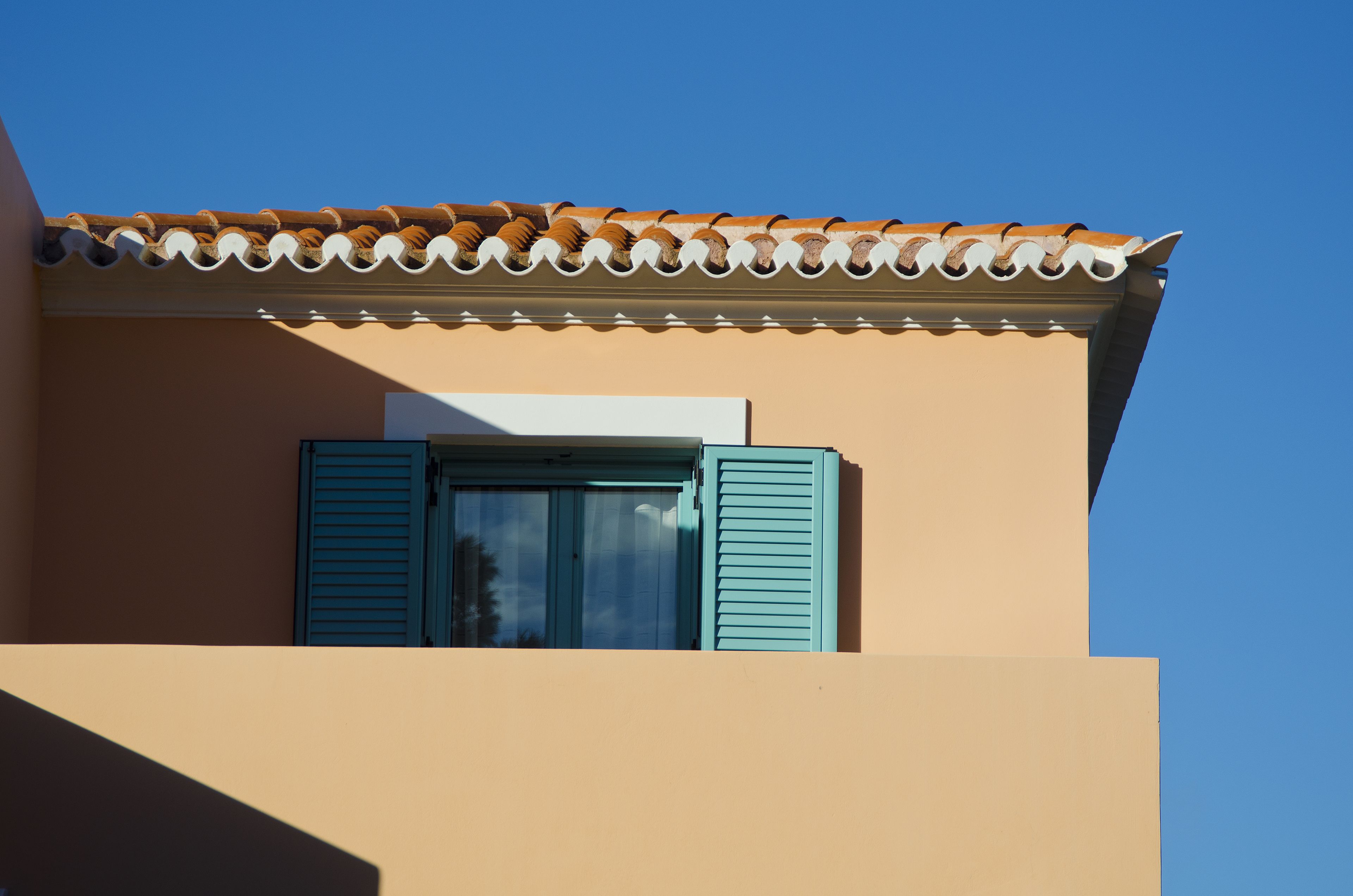 Un edifici amb teulada d'estil i finestra amb persianes blaves.