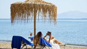 A beach scene with a straw umbrella and two beach chairs. - Makis Inn Resort (Ermionida)
