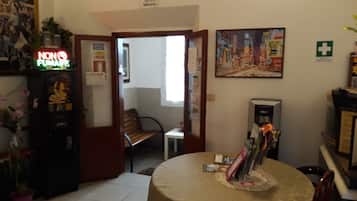 Un soggiorno con un tavolo rotondo, una macchina per caffè, una porta che dà su un’altra stanza e un quadro appeso al muro.