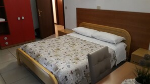 A bed with a patterned bedspread, a wooden headboard, and a bedside table with a lamp.