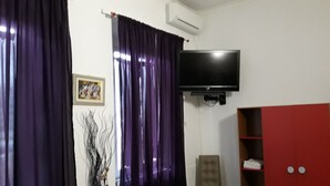 A room with purple curtains, a mounted TV, a framed picture, and a red cabinet. - Hotel Houston (Livorno)