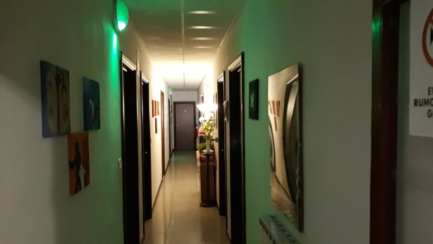 A hallway with doors on both sides, some with signs, and a sign on the right wall. - Hotel Houston (Livorno)