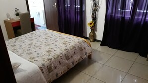 A bedroom with a bed, a desk, a chair, a vase with flowers, and curtains. - Hotel Houston (Livorno)