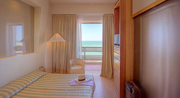 Habitación de hotel con cama, una silla, televisión y vista al mar.