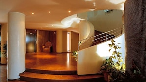 A spacious lobby with a curved staircase, a seating area, and a large plant. - Hotel President (Silvi)