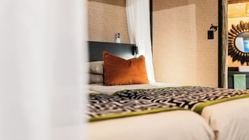 A hotel room with a bed, a nightstand, a mirror, and a wall-mounted telephone.