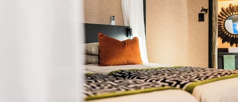 A hotel room with a bed, a nightstand, a mirror, and a wall-mounted telephone.