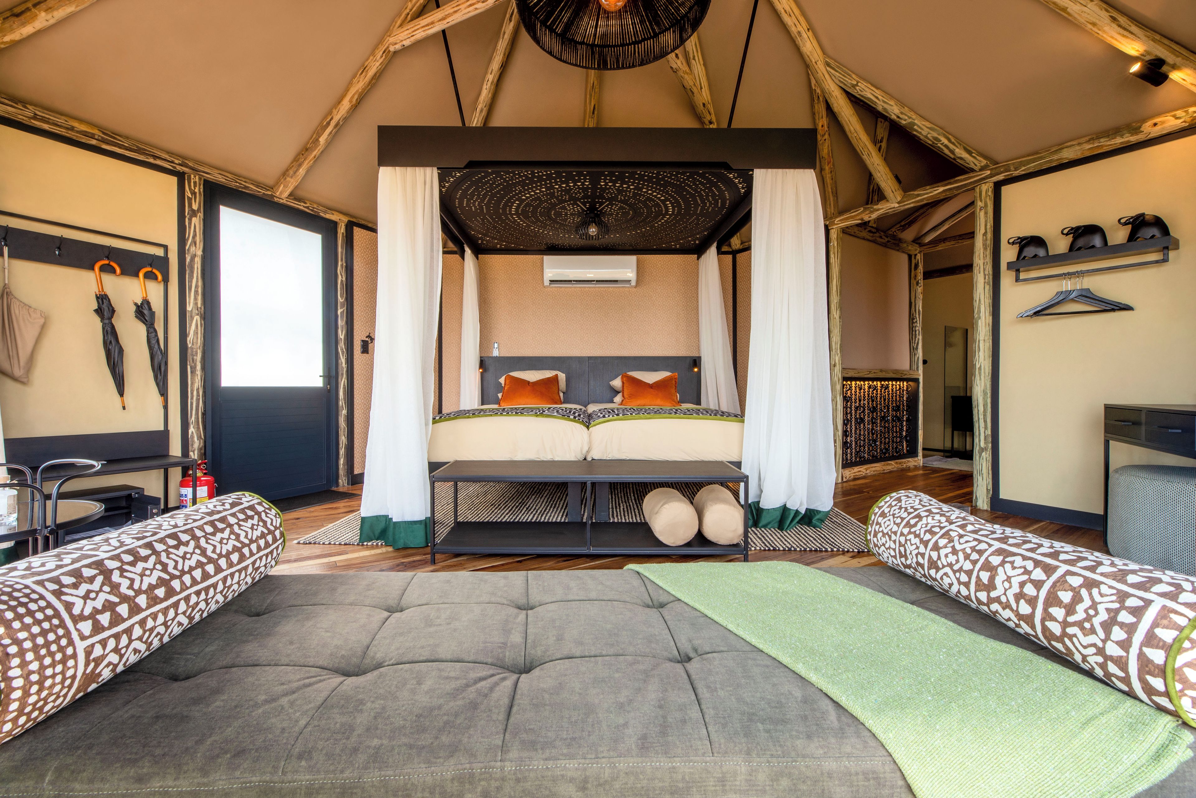 A room with a bed, two sofas, a hanging light fixture, and a ceiling fan.