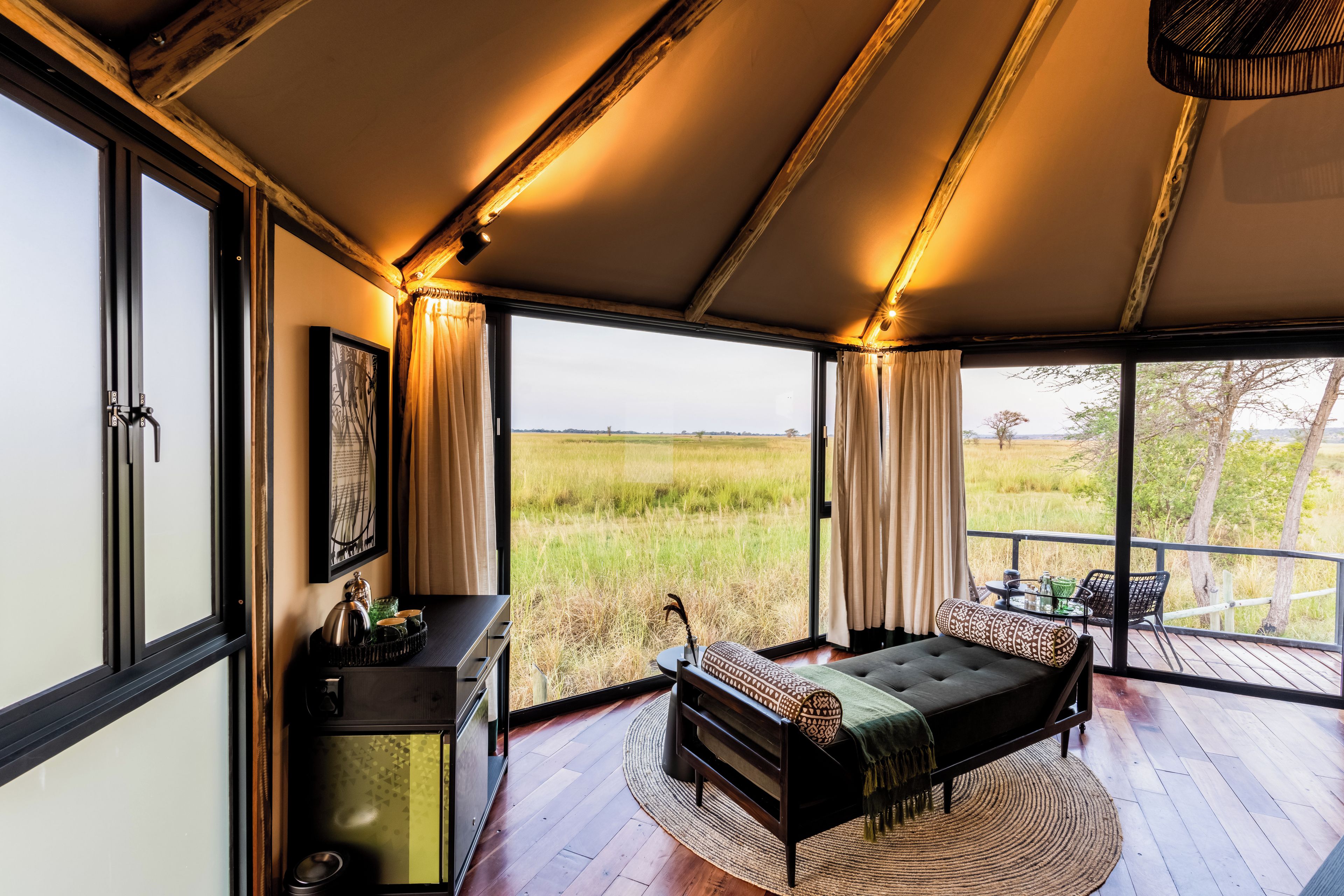 Ein Zimmer mit einem Bett, einem Schreibtisch und einem großen Fenster mit Blick auf ein Feld.