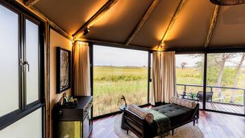 Ein Zimmer mit einem Bett, einem Schreibtisch und einem großen Fenster mit Blick auf ein Feld.