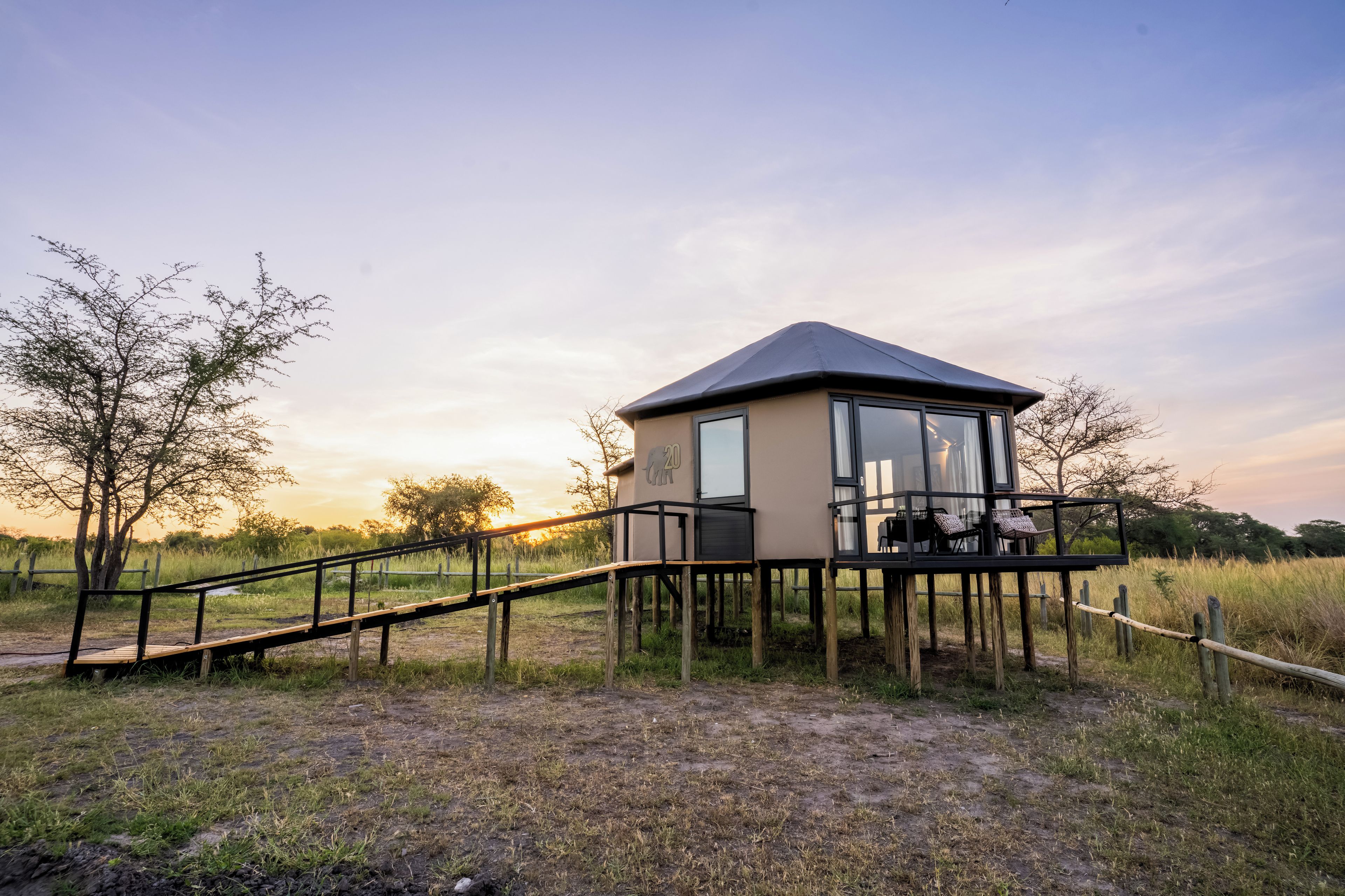 A small, elevated structure with a glass door and a wooden deck, surrounded by natural landscape.