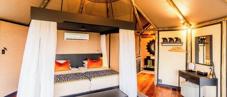 Habitación tipo tienda de campaña con cama, mesita de noche y espejo.