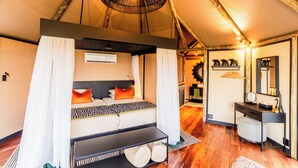 A tent-style room with a bed, bedside table, and a mirror. - Chobe River Camp (Ngoma)