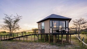 A single-story structure with a balcony, a wooden deck, and a view of the surrounding landscape. - Chobe River Camp (Ngoma)